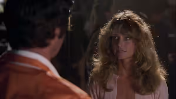 Pamela (Farrah Fawcett) faces a man in an orange racing uniform