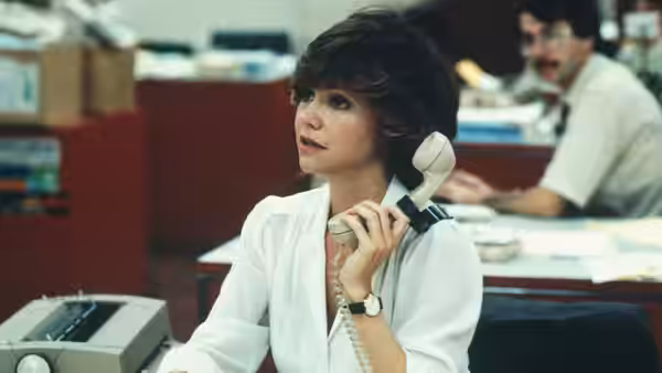Megan Carter (Sally Field) answers a telephone at her newsroom desk