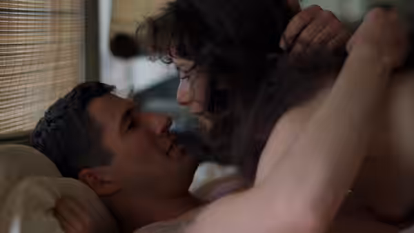 Zack Mayo and Paula Pokrifki embrace closely beside a window