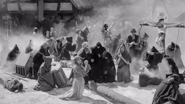 Crowd in medieval robes gathered around a raised cross outdoors