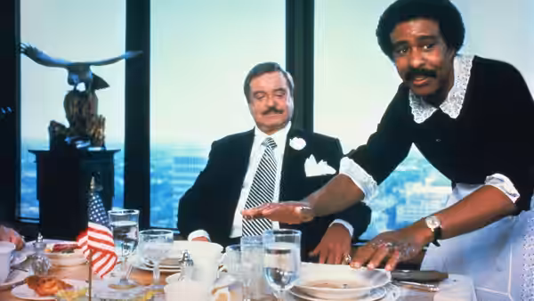 Jack Brown (Richard Pryor) sets the table while U.S. Bates (Jackie Gleason) sits nearby