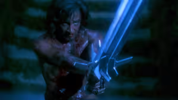 Talon (Lee Horsley) grips his three-bladed sword in a darkened setting