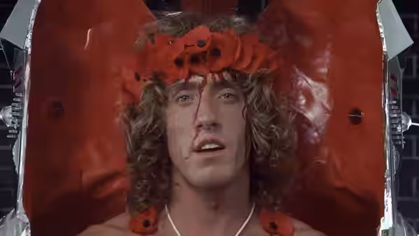 Tommy (Roger Daltrey) sits framed by a red poppy-lined apparatus