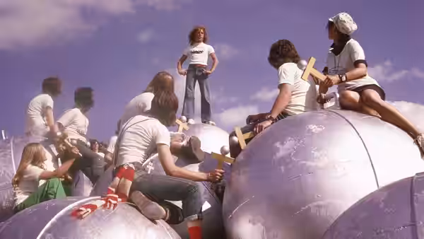 Tommy (Roger Daltrey) stands atop silver spheres as a crowd gathers around him