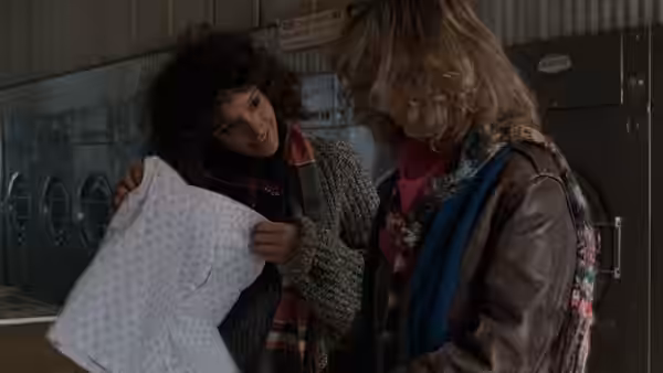 Jeanie Szabo (Sunny Johnson) shows Alex Owens (Jennifer Beals) a white garment by the lockers