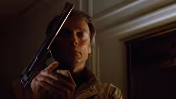 Harry Callahan (Clint Eastwood) holds his revolver inside a dim room