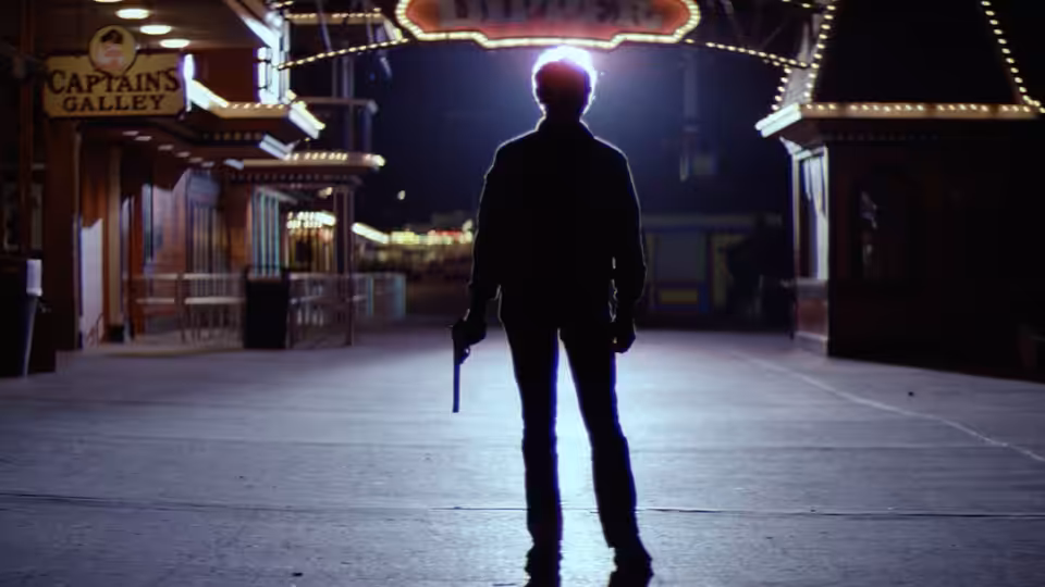 Harry Callahan (Clint Eastwood) stands with a revolver beneath the lights of an amusement park