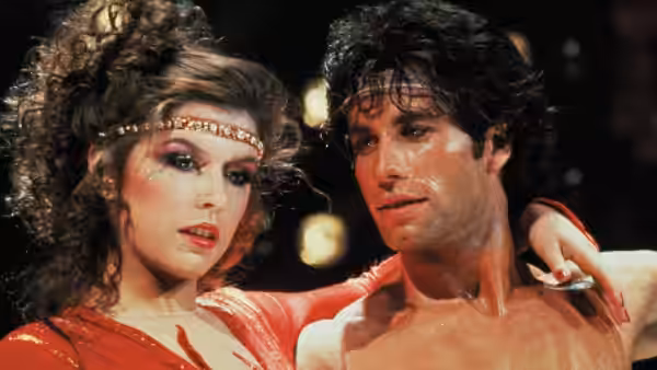 Laura and Tony Manero stand together beneath the stage lights