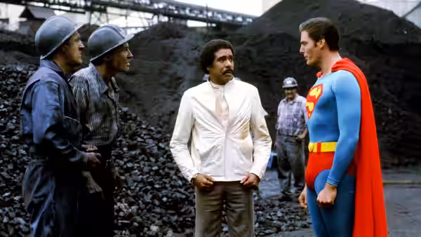 Superman (Christopher Reeve) speaks with Gus Gorman (Richard Pryor) among miners at a coal mine