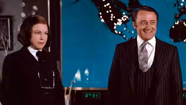 Ross Webster (Robert Vaughn) smiles beside Vera Webster (Annie Ross) in a control room