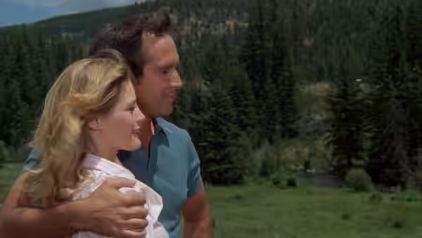 Clark Griswold embraces Ellen on a roadside overlooking a forested mountain slope