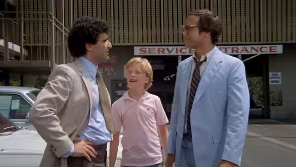 Clark Griswold and Rusty stand with a man outside a service entrance