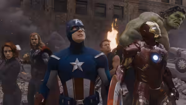 Captain America, Iron Man and Hulk standing amid city rubble and smoke