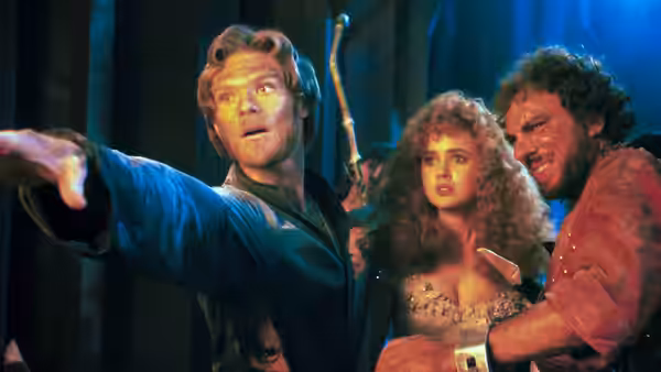 Prince Colwyn (Kenneth Marshall) points ahead while Lyssa (Lysette Anthony) stands beside a man holding her