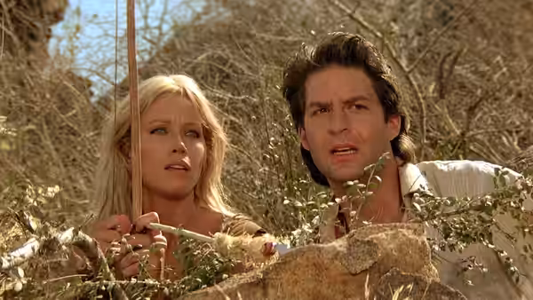 Sheena (Tanya Roberts) and Vic Casey (Ted Wass) peer over a rocky ledge