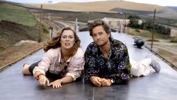 Joan Wilder and Jack Colton lie on the roof of a moving vehicle