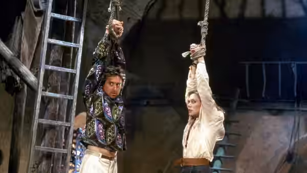 Jack Colton and Joan Wilder hang from ropes inside a stone structure