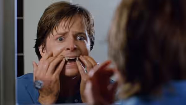 Scott Howard (Michael J. Fox) examines his teeth in a mirror, startled by his reflection