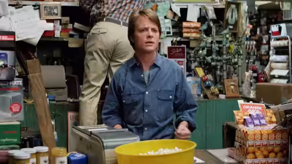 Scott Howard (Michael J. Fox) stands behind a store counter surrounded by merchandise