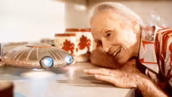 Faye Riley smiles at a tiny hovering spacecraft on the kitchen counter