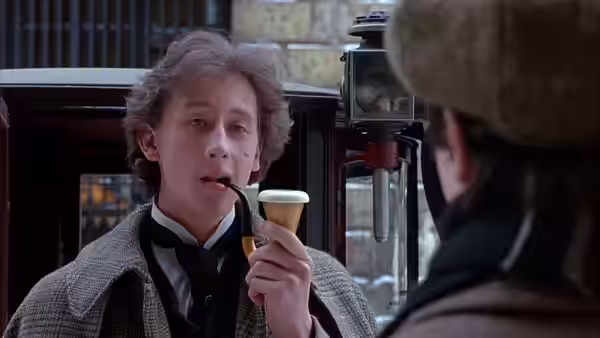 Sherlock Holmes (Nicholas Rowe) smokes his pipe beside a carriage, facing John Watson