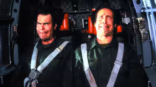 Emmett Fitz-Hume (Chevy Chase) and Austin Millbarge (Dan Aykroyd) sit strapped into aircraft seats
