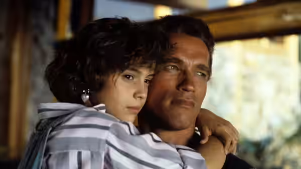 John Matrix (Arnold Schwarzenegger) holds Jenny (Alyssa Milano) close inside a building