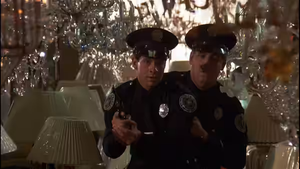 Two uniformed officers cautiously aim a handgun inside a shop filled with glassware