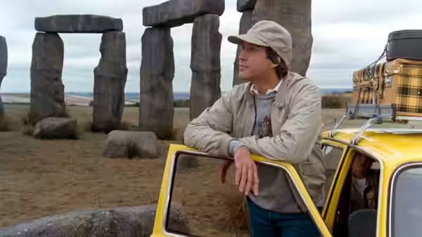 Clark (Chevy Chase) leans on the open door of his car beside Stonehenge