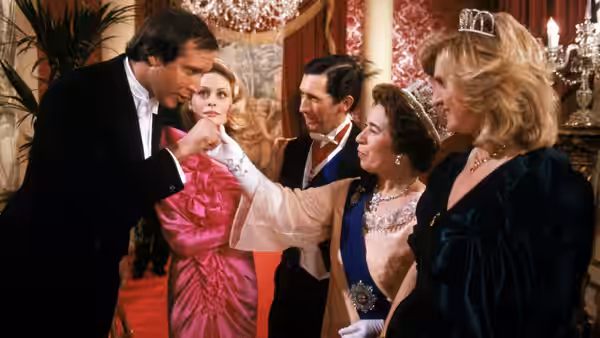Clark (Chevy Chase) greets a woman at a formal gathering as Ellen (Beverly D'Angelo) watches