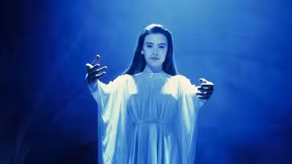 The Space Girl (Mathilda May) in a white gown reaches forward under blue light