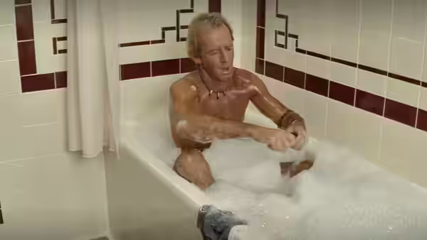 Mick Dundee (Paul Hogan) sits in a foam-filled bathtub in a tiled bathroom