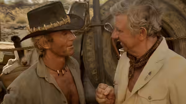 Mick Dundee (Paul Hogan) talks with Walter Reilly (John Meillon) beside a vehicle