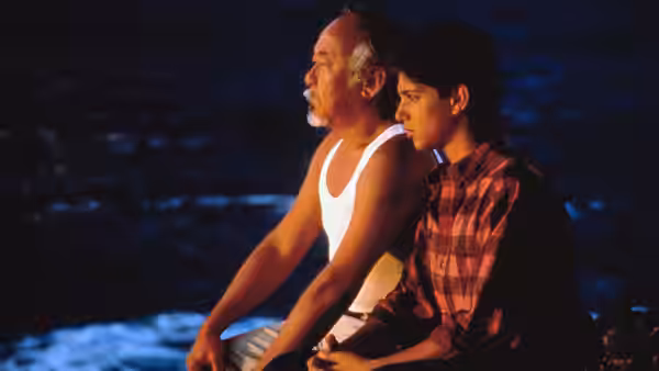 Miyagi (Pat Morita) and Daniel (Ralph Macchio) sit beside the water at night