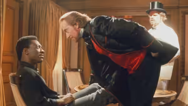 Sardo Numspa (Charles Dance) leans toward Chandler Jarrell (Eddie Murphy) as a guard watches