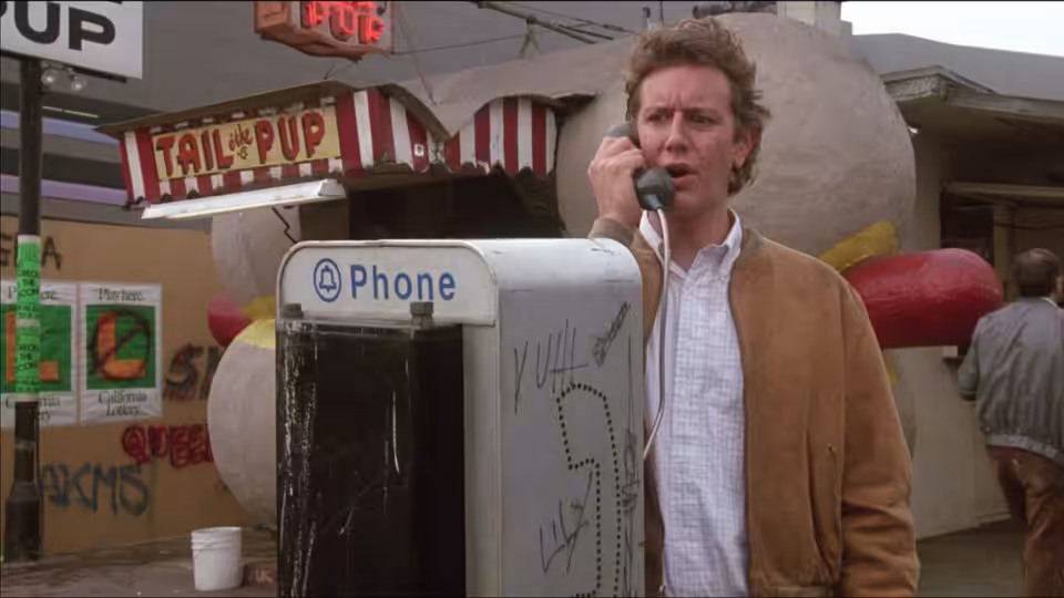 Ken Kessler (Judge Reinhold) speaks on a pay phone outside a storefront
