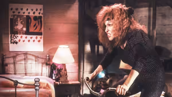 Barbara Stone (Bette Midler) leans over an exercise bike in her bedroom
