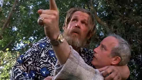 Jerry Baskin (Nick Nolte) points upward while holding Dave Whiteman close beneath the trees
