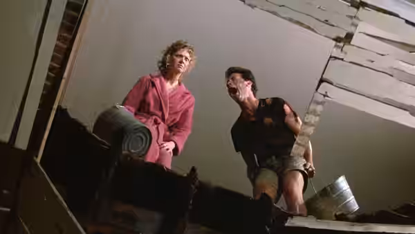 Anna and Walter peer down through a hole in the damaged floor