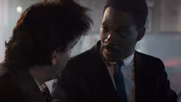 Axel Foley speaks closely with Billy Rosewood in a dim room