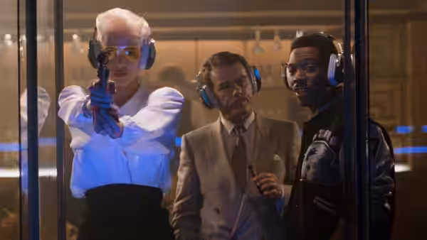 Karla Fry (Brigitte Nielsen) aims a gun beside Maxwell Dent and Axel Foley behind glass