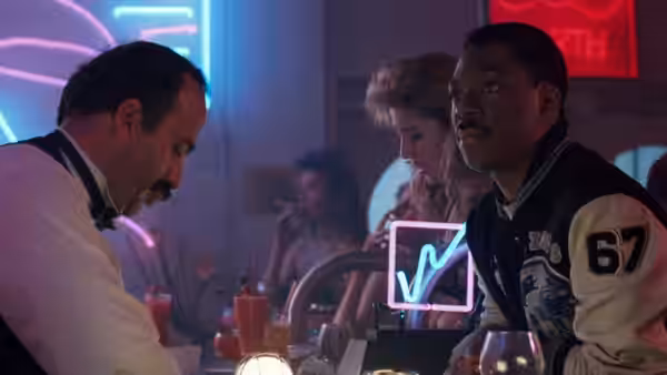Axel Foley sits at a neon-lit bar beside a bartender