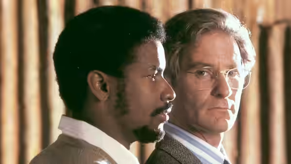 Steve Biko (Denzel Washington) and Donald Woods (Kevin Kline) sit side by side indoors