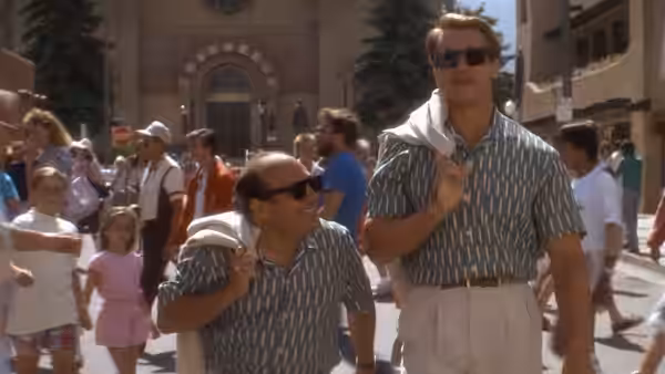 Julius and Vincent walk through a crowded plaza in matching shirts