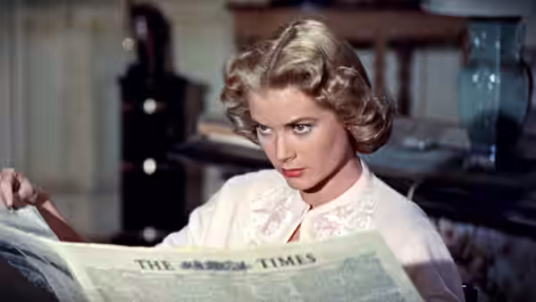 Margot Wendice (Grace Kelly) reads The Times newspaper while seated at a desk