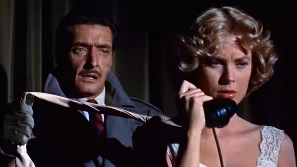 Tony Wendice (Ray Milland) stands behind Margot Wendice (Grace Kelly) holding a tie as she speaks on the phone