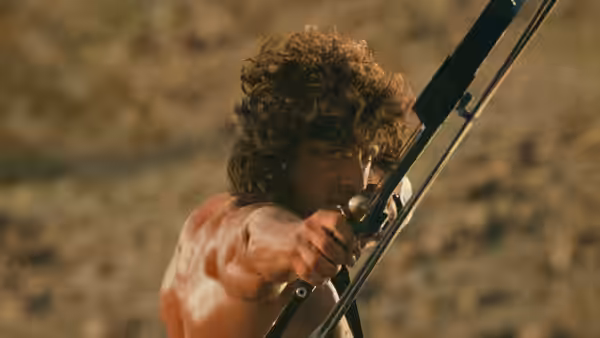 John Rambo (Sylvester Stallone) aims a bow in the rugged countryside