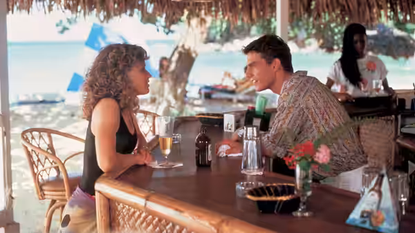 Brian Flanagan and Jordan Mooney talk across a table at a beachside bar