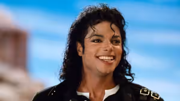 Michael Jackson smiles against a bright blue backdrop