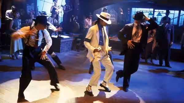 Michael Jackson dances in a white suit between two men in a dim club
